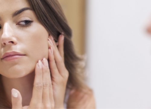Woman checking her face in the mirror for acne scarring
