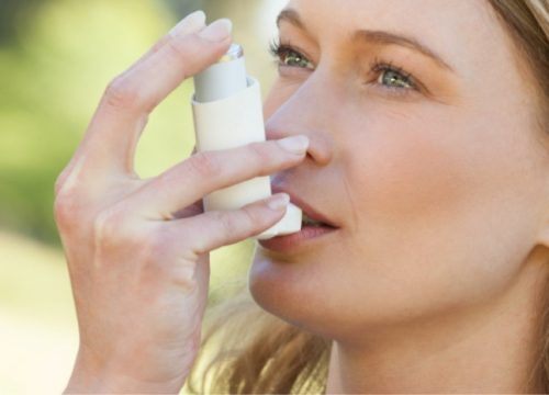 Woman with asthma using an inhaler