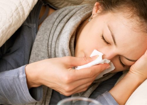Woman with a common cold blowing her nose with a tissue