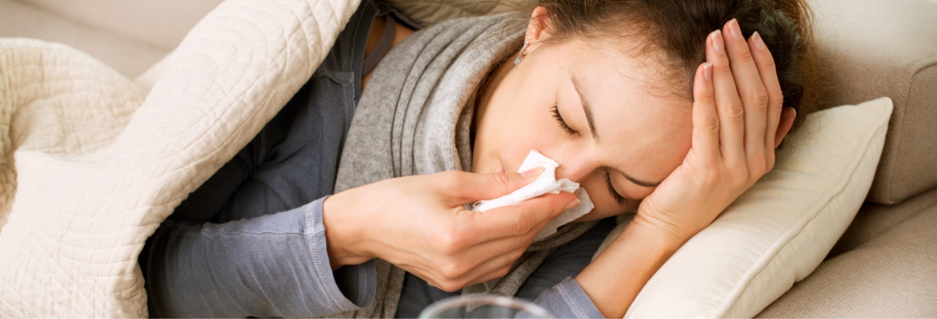 Woman with a common cold blowing her nose with a tissue